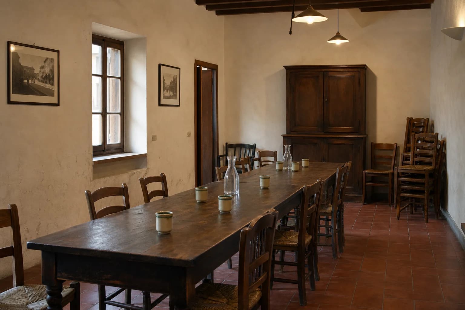 A long wooden table and worn chairs arranged for a gathering in a simple Siena Contrada society room